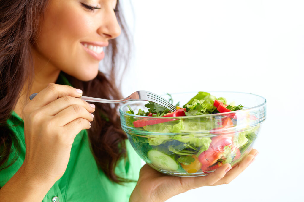 Woman eating fresh vegetables salad