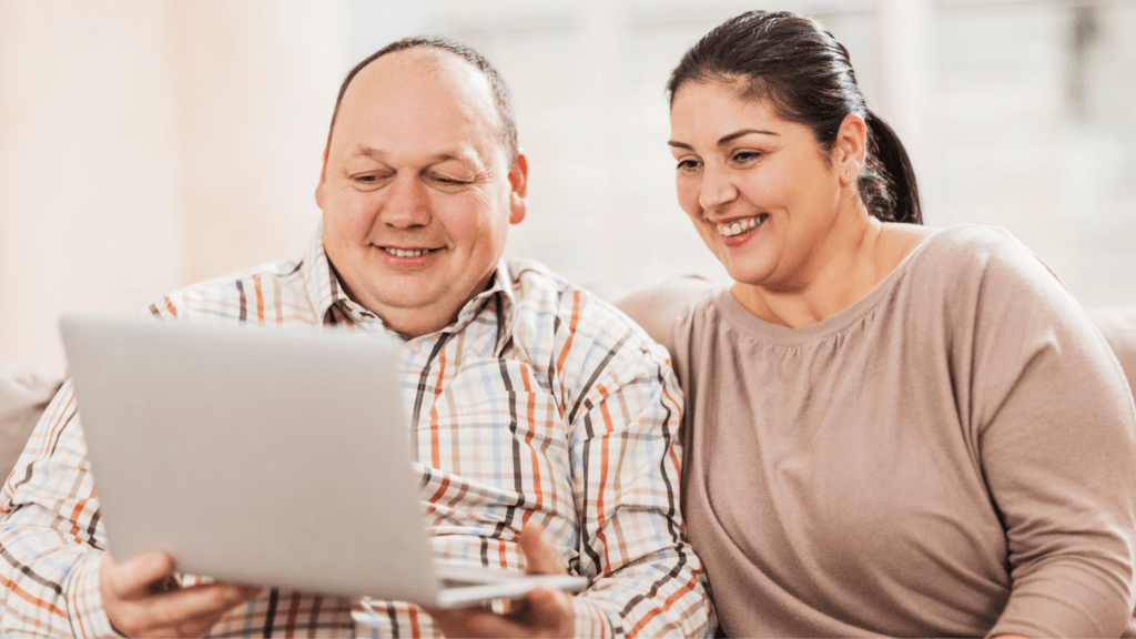 Overweight couple smiling looking at a laptop